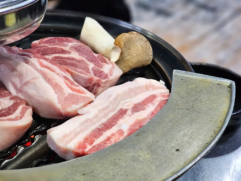 불판 위에 목살과 버섯이 놓여 있는 모습