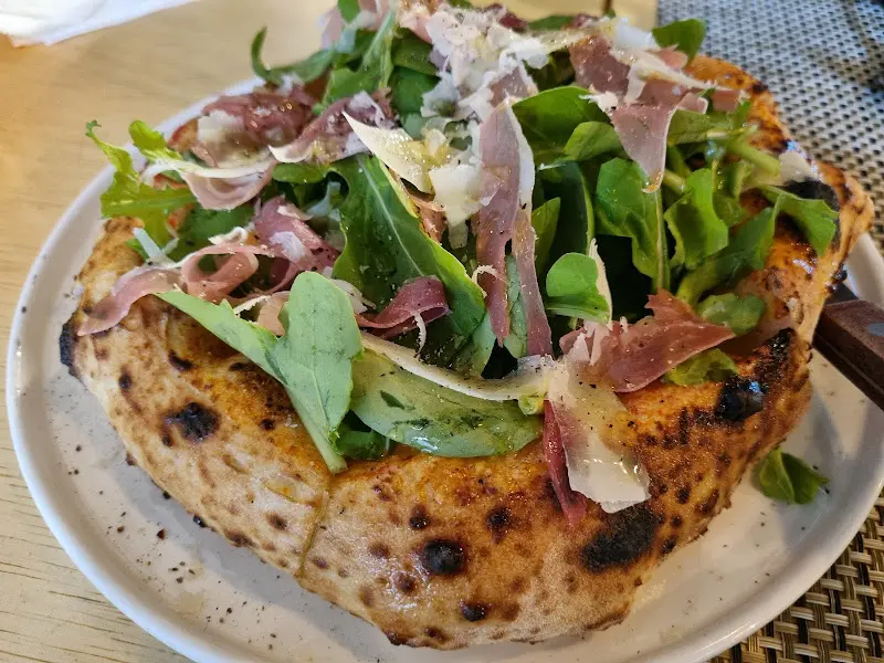 신선한 루꼴라와 프로슈토가 올려진 화덕 피자