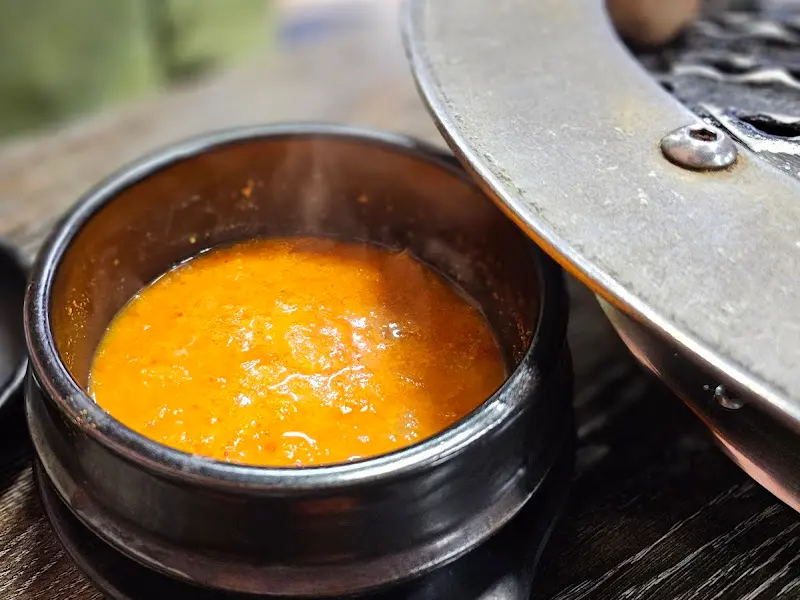 고기 불판 옆에 놓인 뚝배기 안의 비지찌개