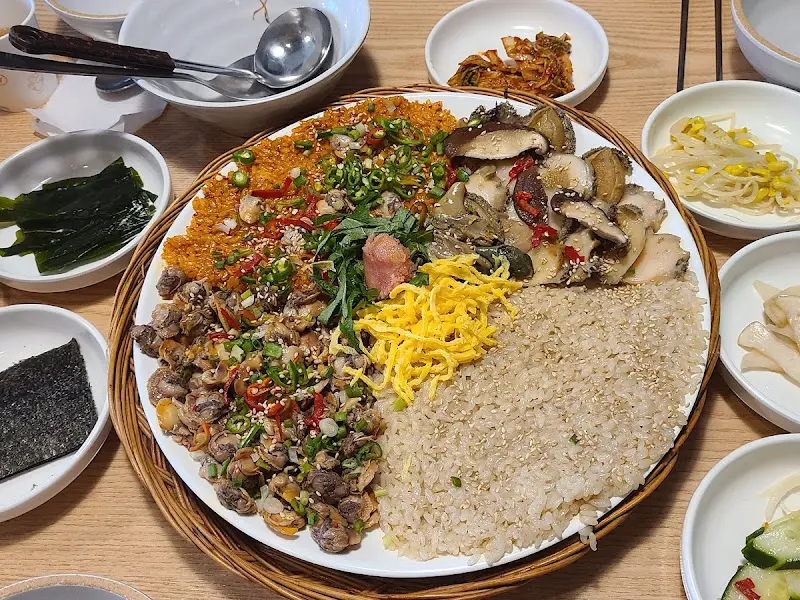 꼬막, 밥, 채소가 푸짐하게 담겨있는 꼬막 비빔밥 한 상차림