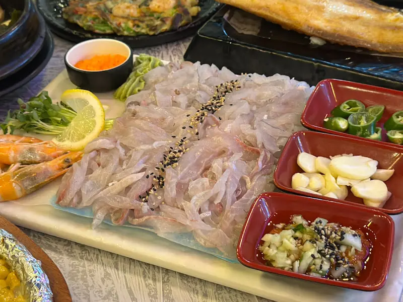 세꼬시, 곁들임 야채, 소스, 새우, 생선구이 등이 한 상 가득 차려진 모습