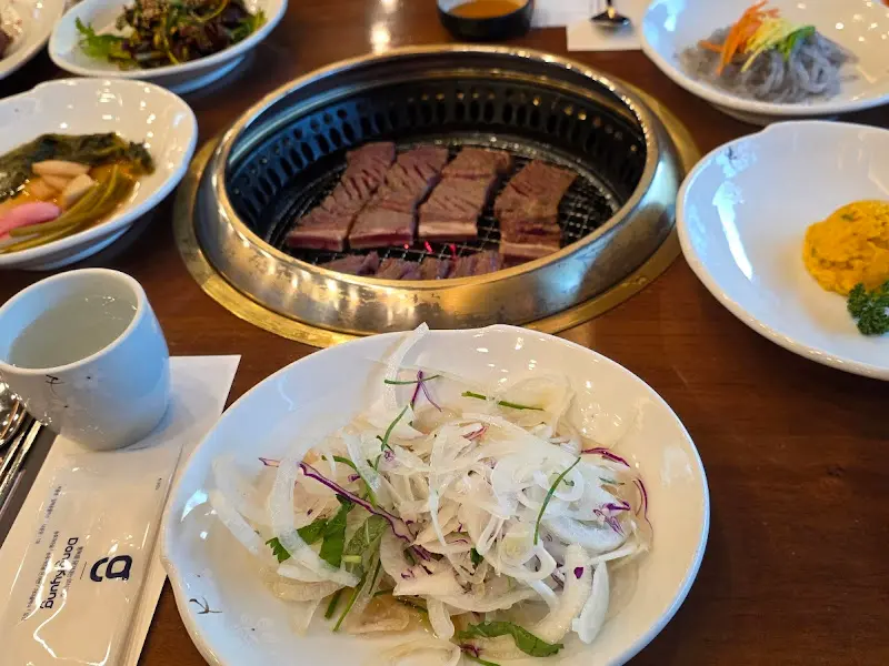 숯불 위에 올려진 송추갈비와 다양한 밑반찬들