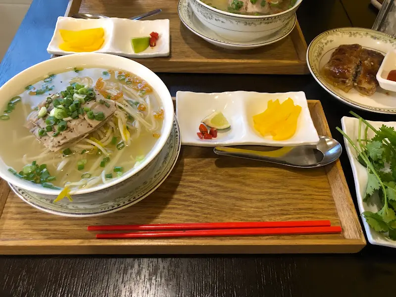 나무 쟁반 위에 놓인 후띠우 한 그릇과 각종 소스, 넴이 담긴 접시