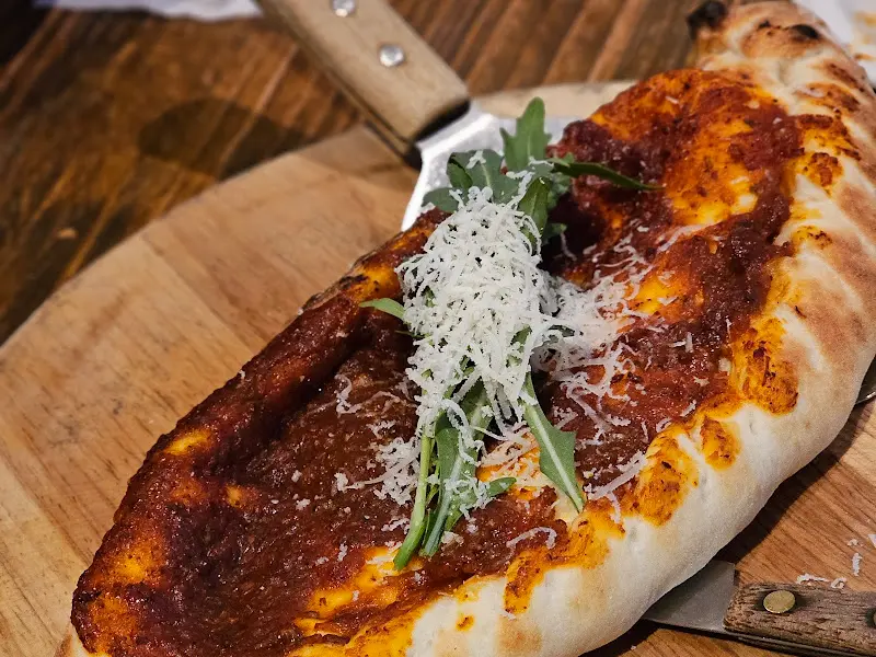 나무 도마 위에 올려진 깔조네 피자