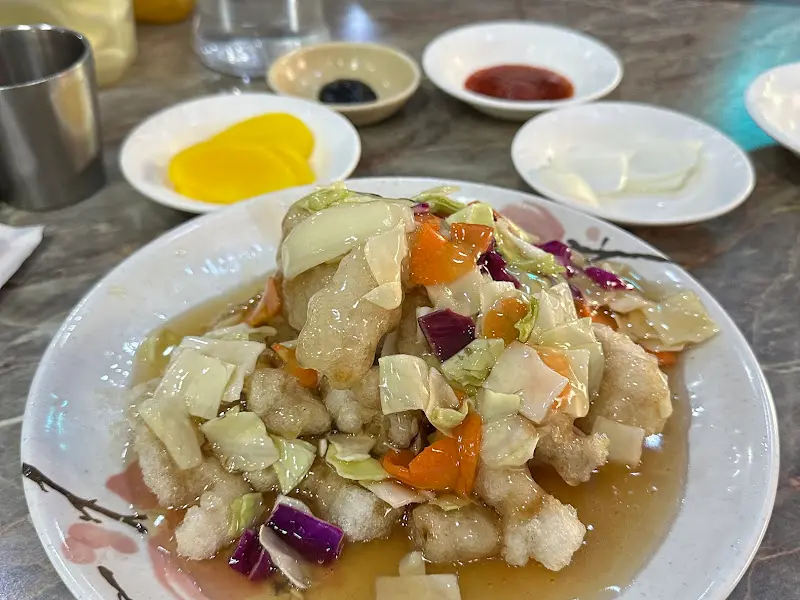 탕수육 위에 양배추, 당근, 자주색 양배추 등 다채로운 색감의 채소가 곁들여져 있다.