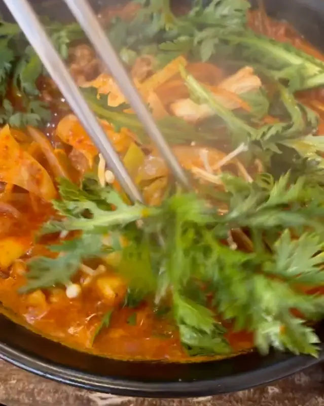 젓가락으로 우동 속 쑥갓을 들어올리는 모습