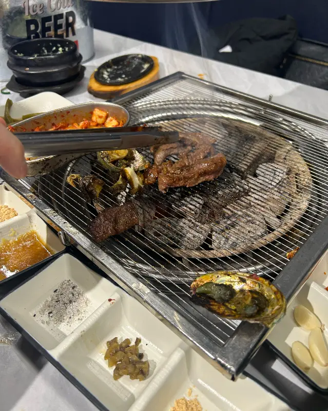 숯불 위에서 지글거리는 고기와 전복