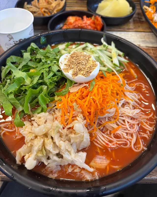 비빔국수, 김치, 단무지, 어묵볶음 등이 담긴 테이블