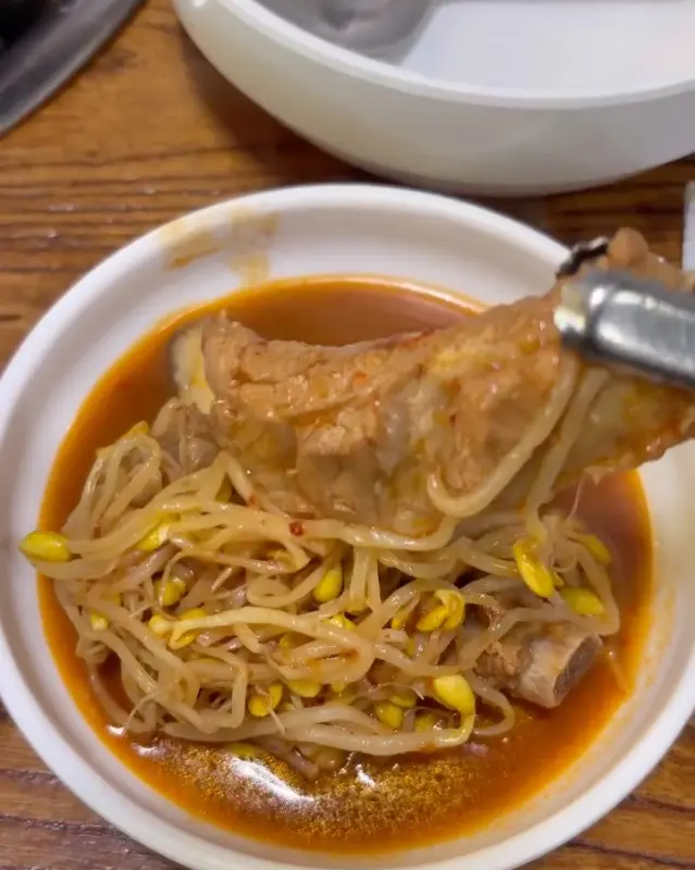 젓가락으로 들어올린 등갈비와 콩나물의 조화