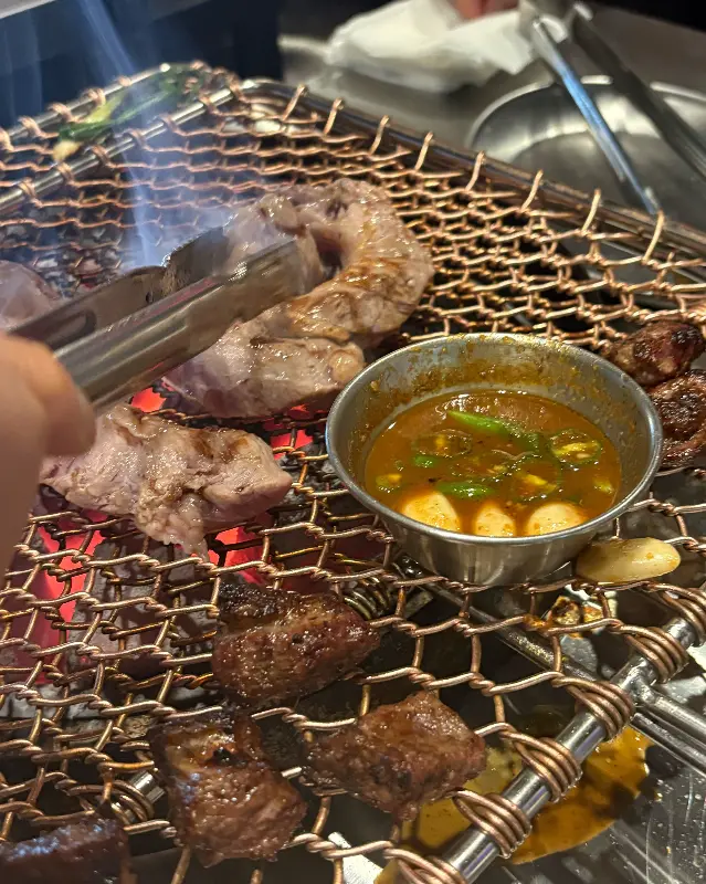 노릇노릇 익은 갈매기살을 집어 특제 소스에 찍어 먹는 모습