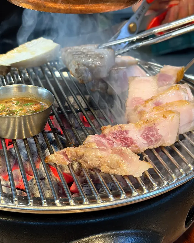 숯불 위에서 익어가는 흑돼지와 멜젓