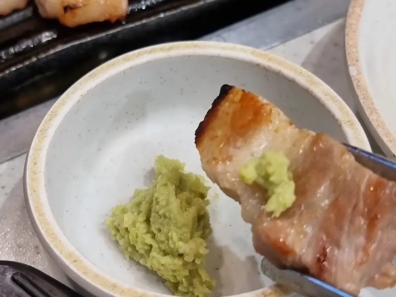 잘 구워진 고기에 와사비를 올려 먹는 모습