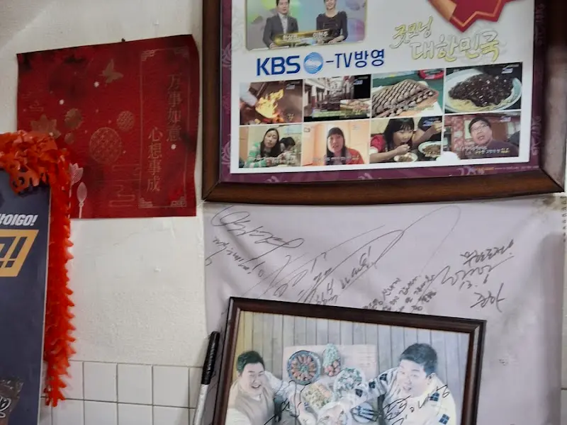 벽에 걸린 방송 출연 사진과 유명인들의 사인
