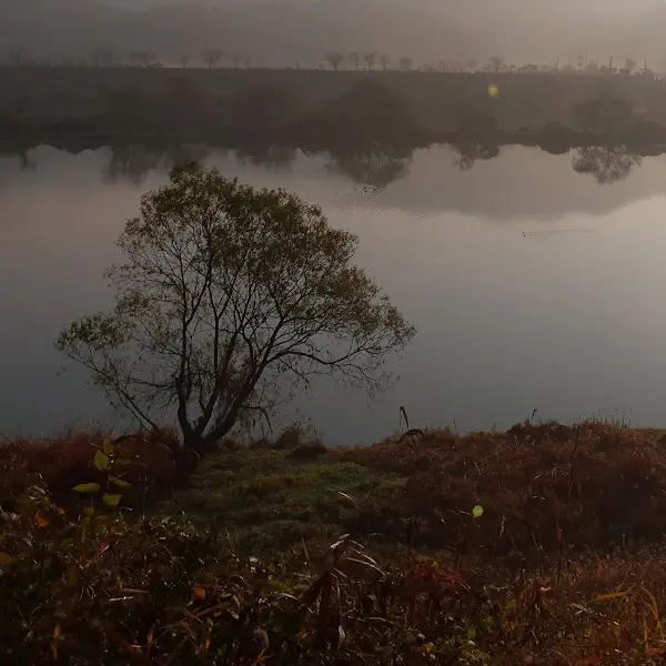 잔잔한 물결이 일렁이는 호수와 그 위에 드리워진 석양의 모습