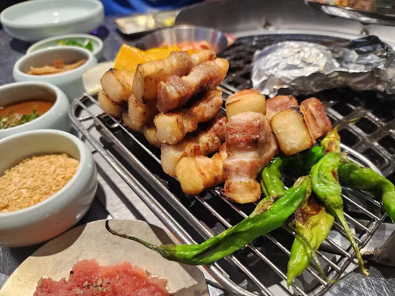 잘 구워진 숙성 삼겹살이 철제 그릴 위에 올려져 있는 모습