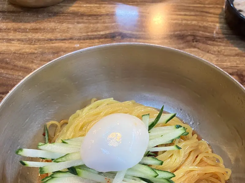 비빔 밀면 위에 오이와 계란 고명이 올려진 모습