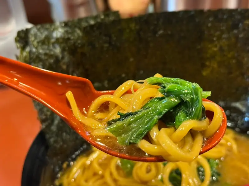 숟가락으로 라멘 국물과 면, 채소를 함께 떠먹는 모습