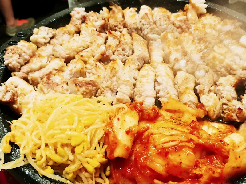 불판 위에서 익어가는 꽃삼겹살과 김치, 콩나물