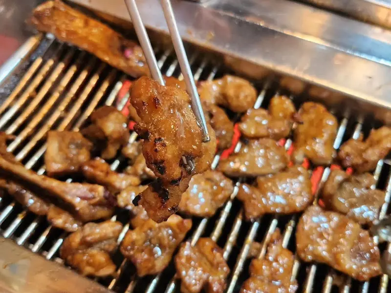 집게로 들어올린 윤기 흐르는 돼지갈비