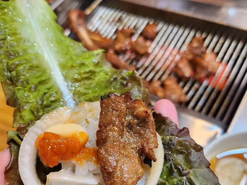 돼지갈비 한 점을 상추쌈에 싸서 든 모습