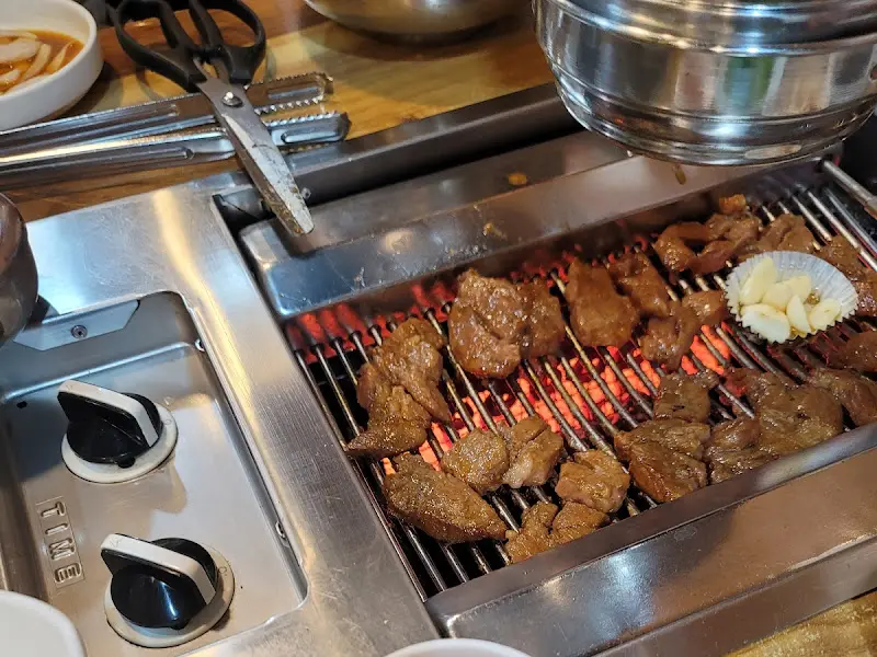 불판 가득 올려진 돼지갈비와 구운 마늘