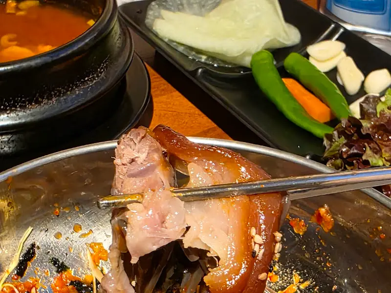순두부찌개, 쌈 채소, 곁들임 반찬과 함께 제공되는 족발