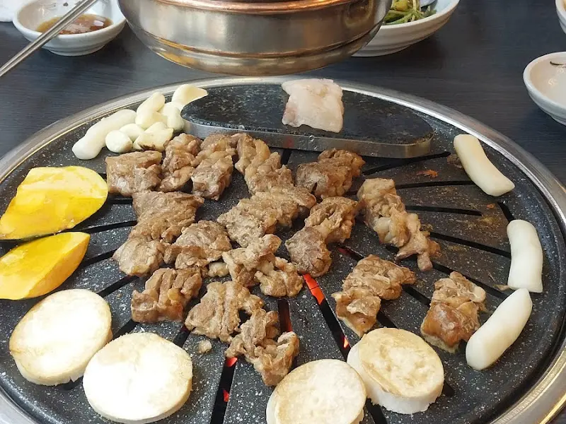 불판 위에 올려진 돼지갈비와 떡, 단호박