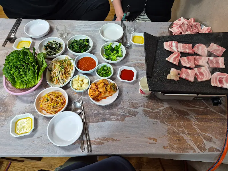 불판 위에 냉삼, 김치, 마늘을 올려 구워먹는 모습