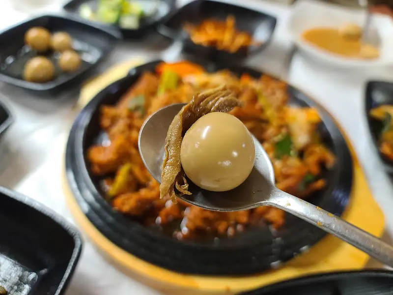 숟가락 위에 제육볶음과 메추리알을 함께 올린 모습