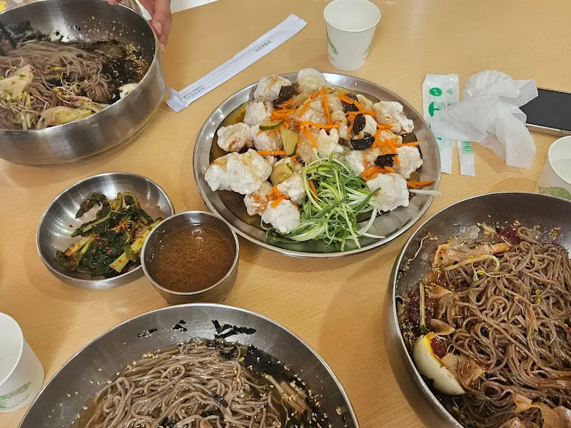 탕수육, 막국수, 만두가 함께 있는 푸짐한 한 상 차림