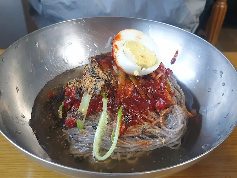 회냉면의 클로즈업 사진. 붉은 양념과 회, 오이, 계란이 조화롭게 보인다.