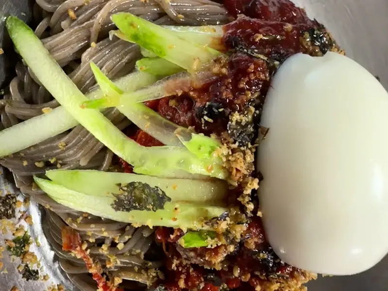 회냉면의 재료들이 클로즈업된 사진. 면, 회, 오이, 계란이 선명하게 보인다.