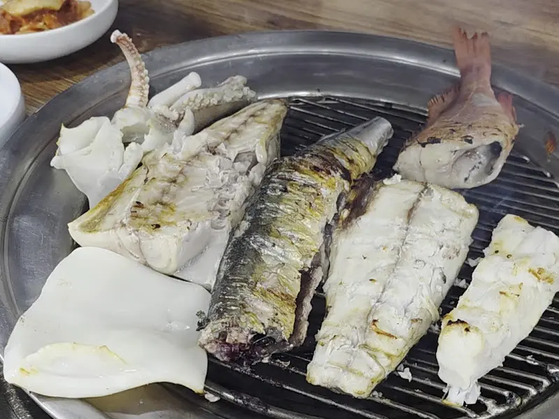 숯불 위에서 구워진 다양한 생선과 오징어