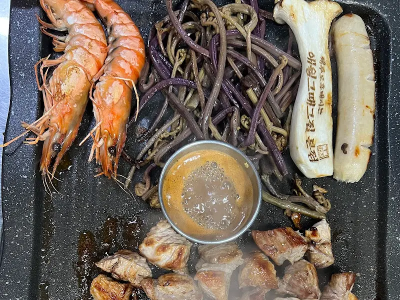 숯불 위에서 흑돼지, 새우, 고사리가 함께 구워지는 모습