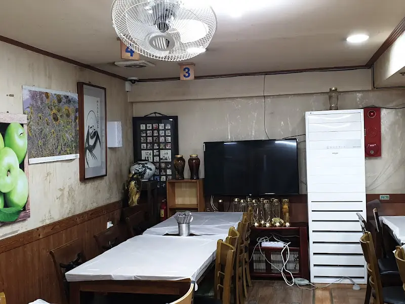 정갈하게 놓인 테이블과 의자, 하동의 풍경 사진이 걸린 식당 내부