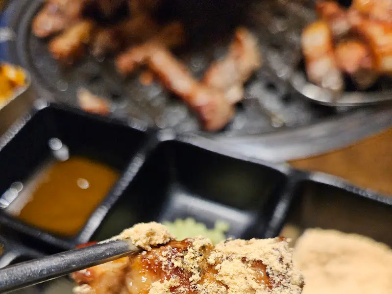 잘 구워진 고기에 콩가루를 묻혀 먹는 모습