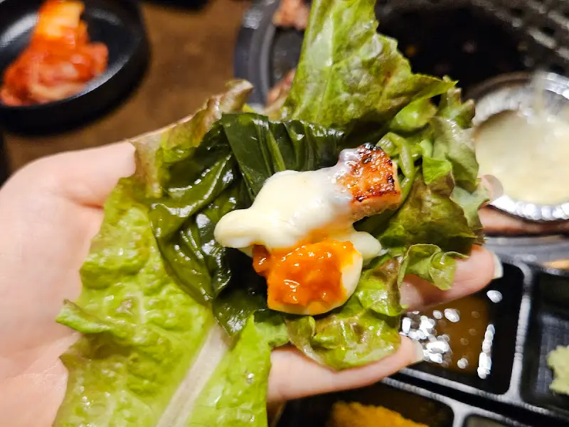 상추쌈에 고기와 쌈장을 얹어 먹는 모습