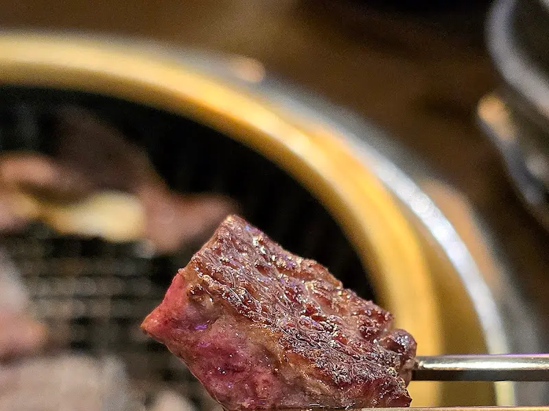 집게로 들어올린 구워진 한우 조각