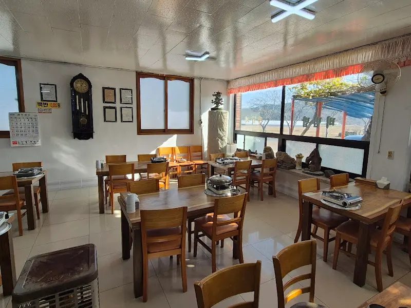 정갈하게 놓여진 나무 테이블과 의자가 놓여진 식당 내부