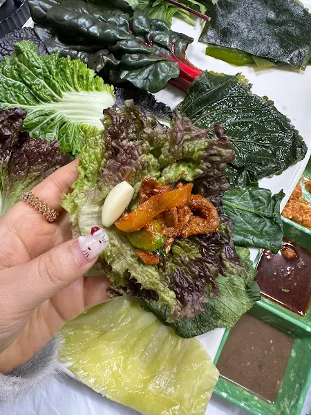 쌈 채소 위에 제육볶음과 김치를 올려 크게 한 쌈