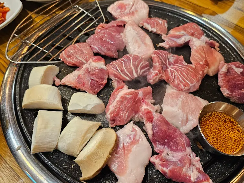 불판 위에서 맛있게 익어가는 뒷고기와 버섯