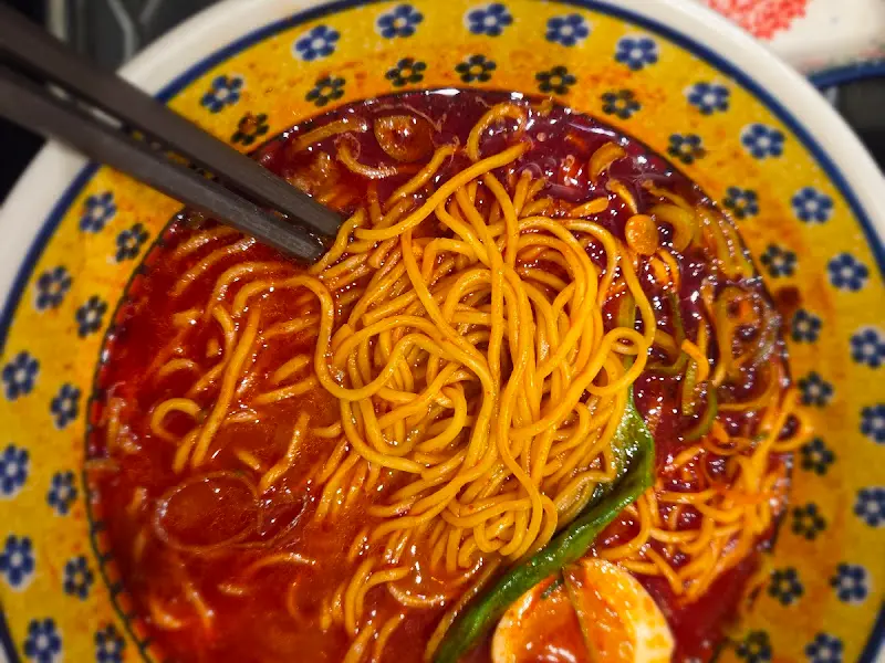 매콤한 국물에 담긴 면 요리를 젓가락으로 집어 올린 모습