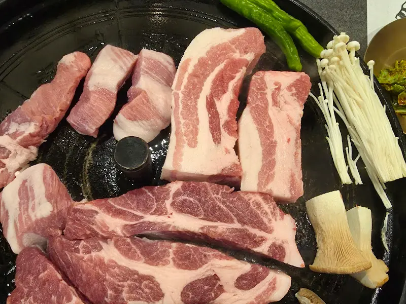 솥뚜껑 위에 올려진 삼겹살과 버섯