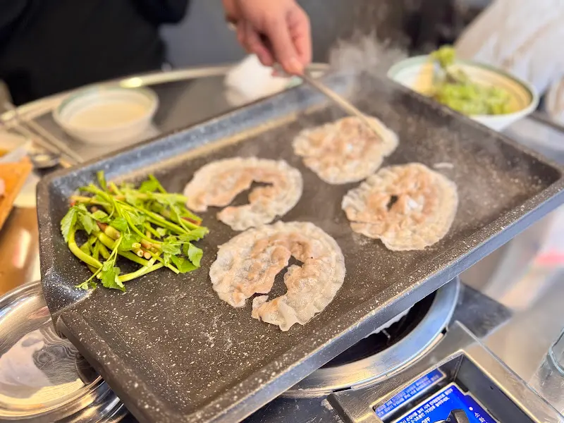 불판 위에서 익어가는 냉삼겹살과 미나리