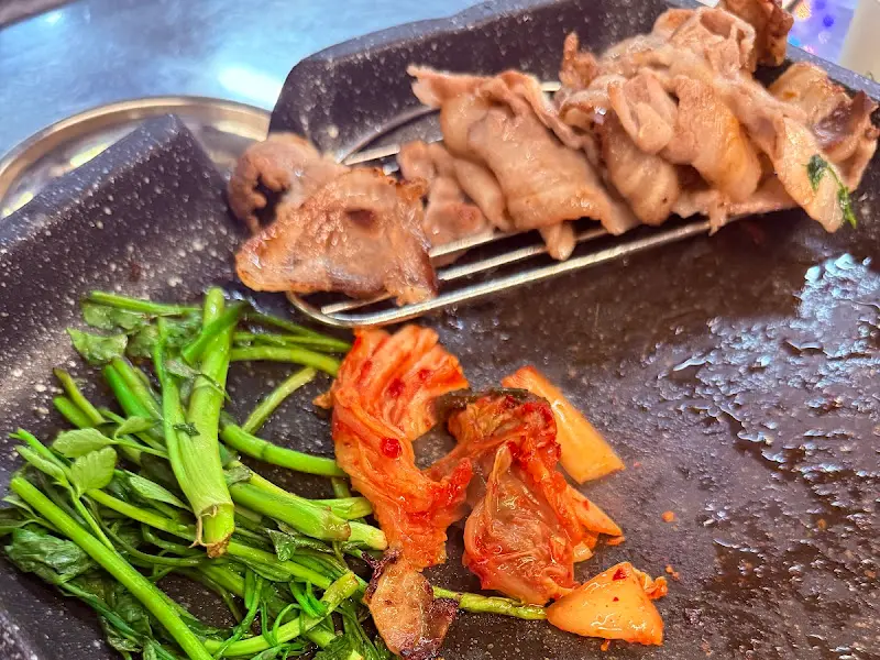 불판 위에 구워진 김치와 미나리