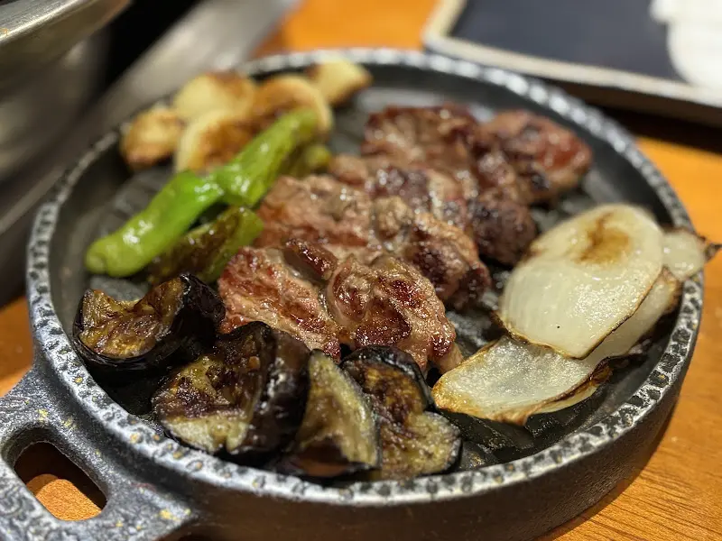 불판에 구워진 양고기, 양파, 가지, 마늘, 고추