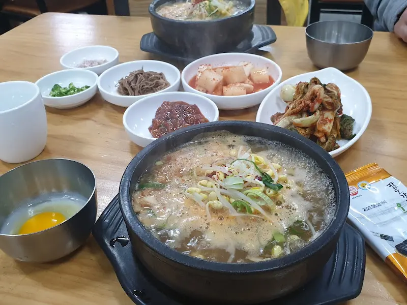 테이블 위에 놓인 콩나물 국밥과 다양한 반찬들