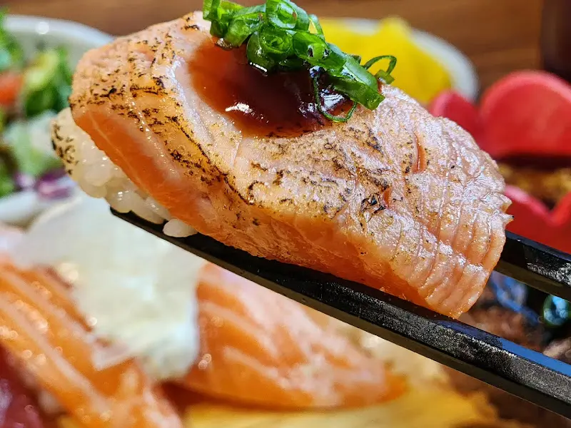 젓가락 위에 올려진 연어 초밥