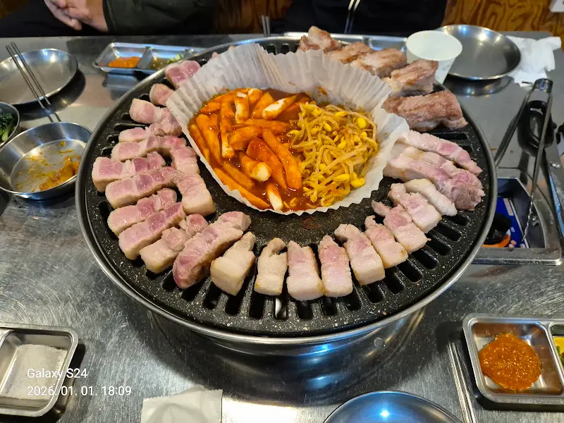 돌판 위의 삼겹살, 떡볶이, 김치, 콩나물