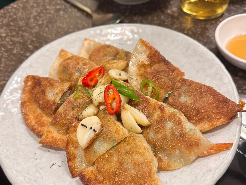 노릇하게 구워진 군만두 위에 구운 마늘이 올려져 있다.